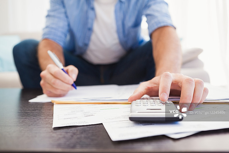 男子在客厅里计算财务图片素材