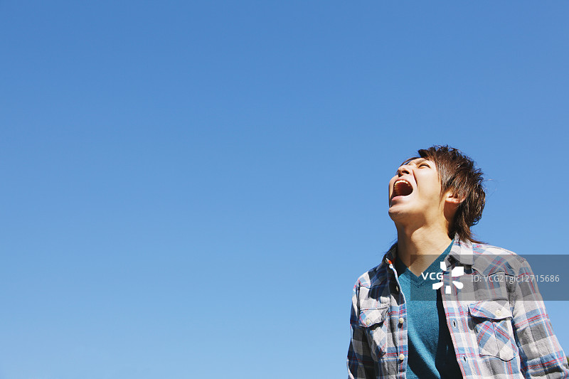 年轻男人对着蓝天喊叫图片素材