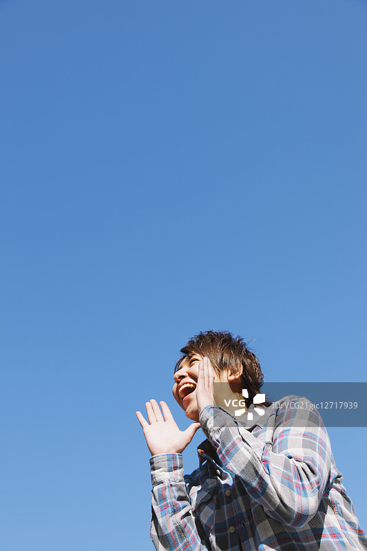 年轻男人对着蓝天喊叫图片素材