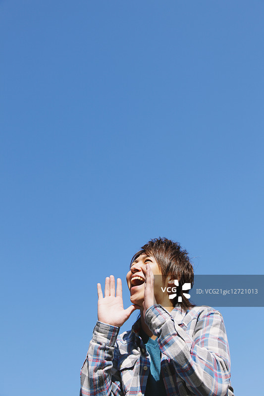 年轻男人对着蓝天喊叫图片素材