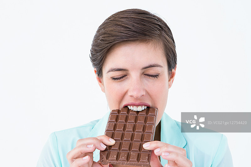 在白色背景上吃巧克力棒的深色头发女人图片素材