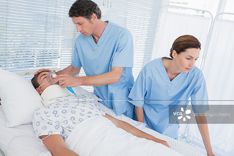 医生在病房里为病人戴氧气面罩图片素材