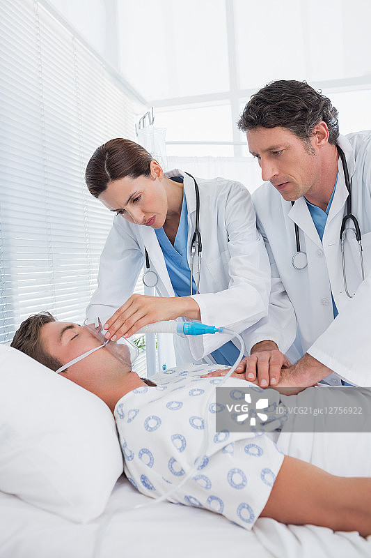 在医院病房里做心脏按摩和戴氧气面罩的焦虑医生图片素材