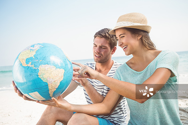 幸福的情侣在海滩上看地球仪图片素材