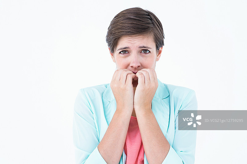 漂亮的深色头发女子在白色背景下焦虑地咬指甲图片素材