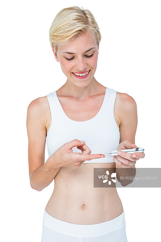 在白色背景下用血糖监测仪做测试的金发女人图片素材