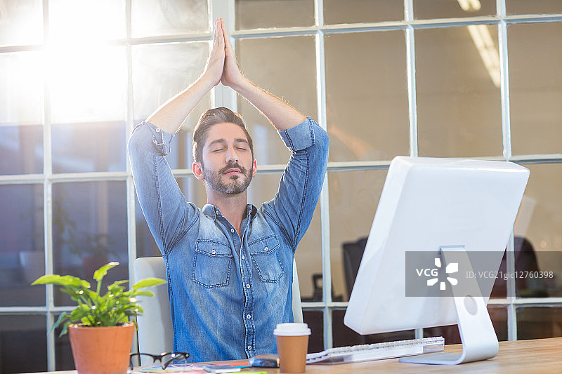 在办公室办公桌前冥想的休闲商人图片素材