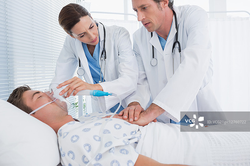 在医院病房里做心脏按摩和戴氧气面罩的焦虑医生图片素材