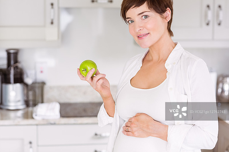 孕妇在厨房的家中吃苹果图片素材