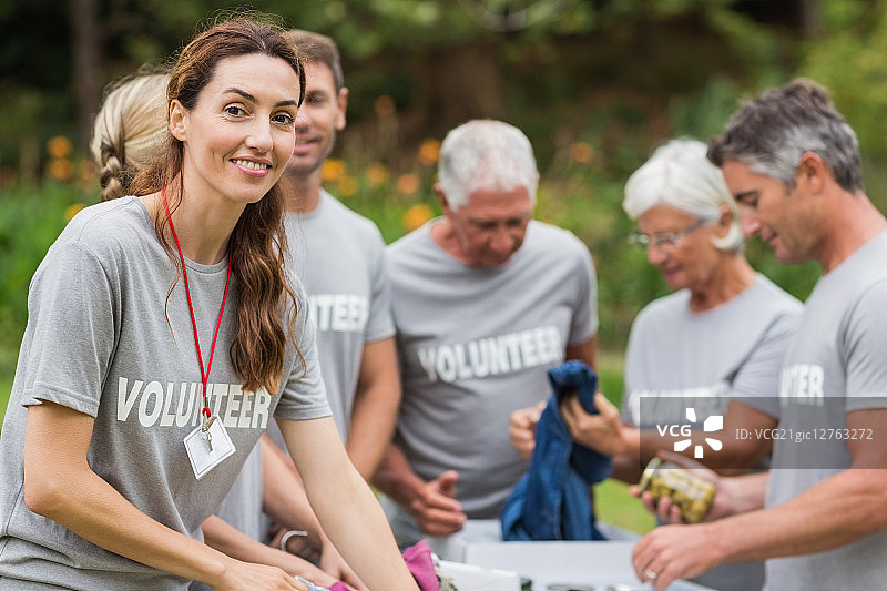 快乐的志愿者在阳光明媚的一天看着捐款箱图片素材