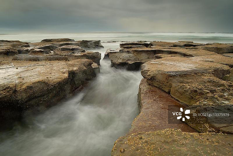 澳大利亚新南威尔士州纽卡斯尔流经岩石的溪流图片素材
