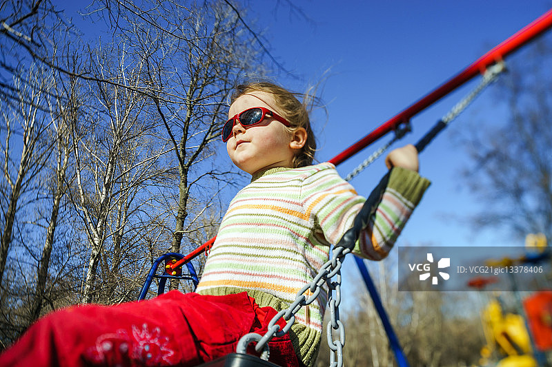 可爱的小女孩在儿童游乐场荡跷跷板图片素材