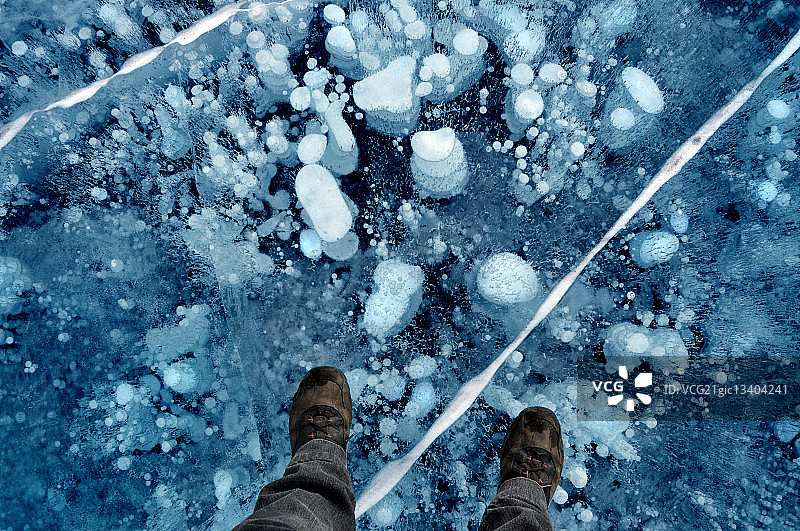 男子站在加拿大落基山亚伯拉罕湖冰面上的低角度照片图片素材