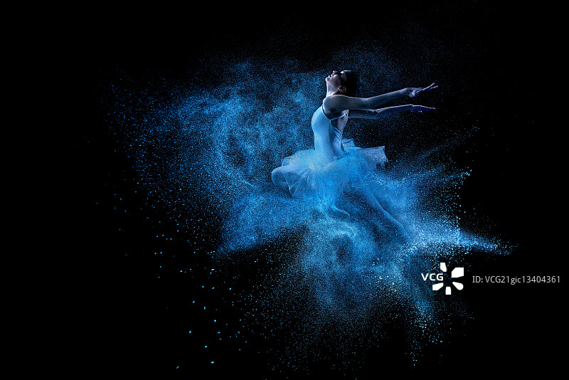 年轻漂亮的舞者跳入蓝色粉末云中图片素材