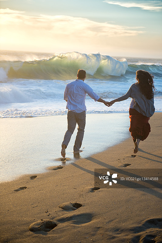 年轻情侣在海滩跑步图片素材