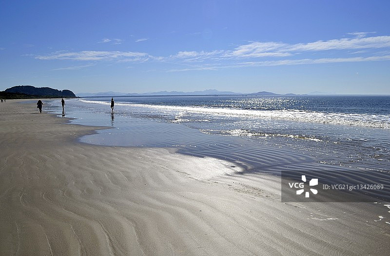 一小群人在阳光明媚的日子里在海滩上散步，巴西巴拉那州蓬塔尔图片素材