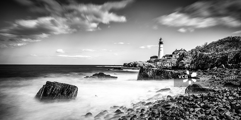 海景：缅因州波特兰的岩石海滩和远处灯塔，美国图片素材