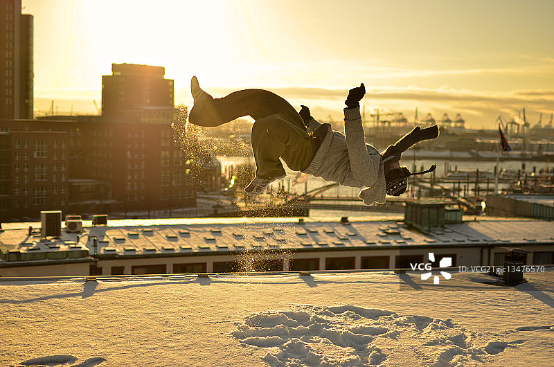 男人在德国汉堡的屋顶上做后空翻图片素材