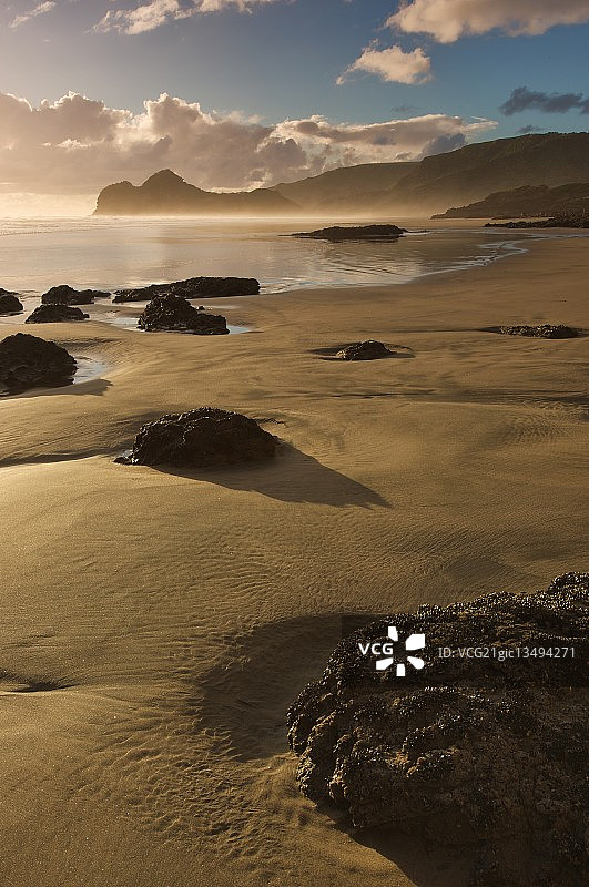 新西兰北岛贝壳海滩日落时分的沙滩岩石图片素材