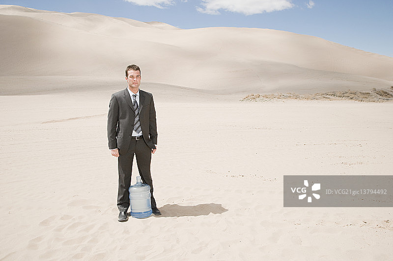 在沙漠里拿着水瓶的男人图片素材