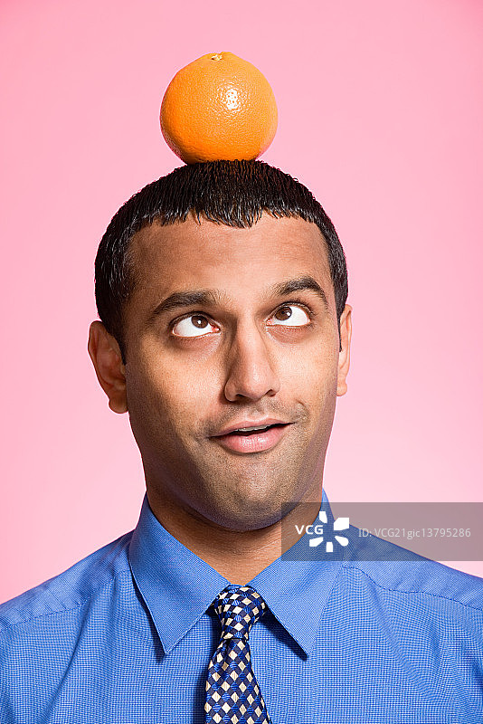 男子头顶橙子保持平衡图片素材