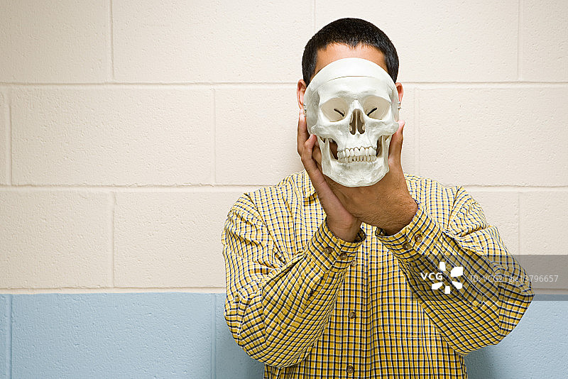 男学生拿着人类头骨图片素材