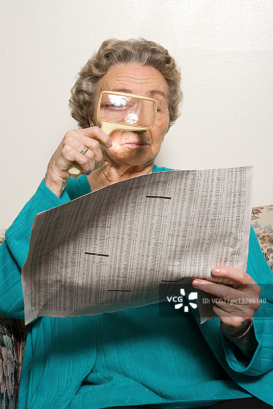 女人用放大镜阅读报纸图片素材