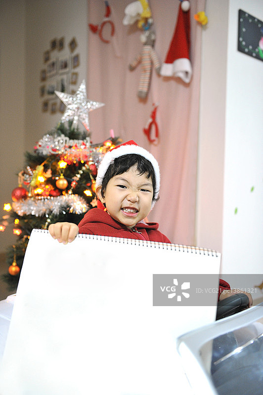 男孩打扮成圣诞老人拿着速写本图片素材