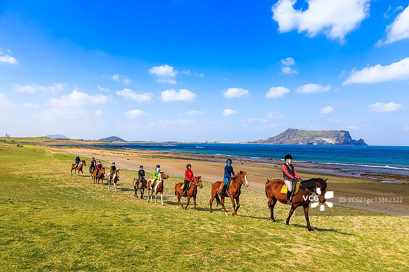 涉地可支，城山日出峰，中国济州岛骑马观光的游客图片素材
