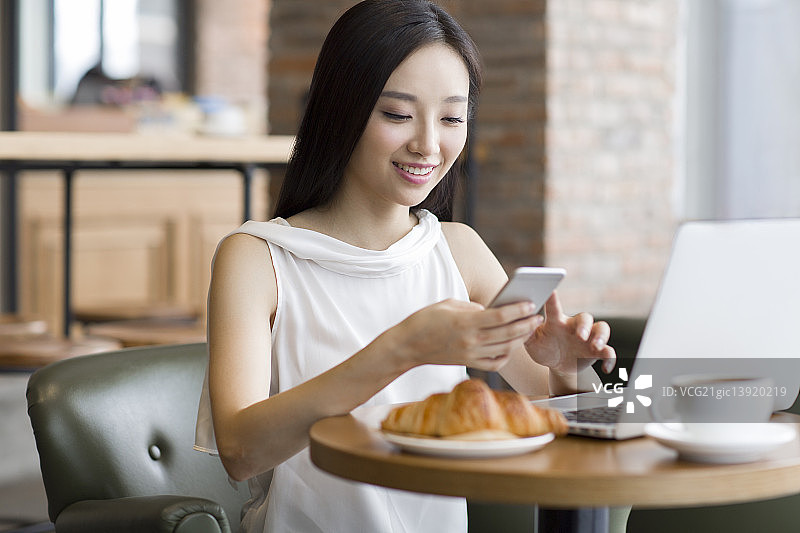 年轻女士在咖啡厅使用笔记本电脑工作图片素材