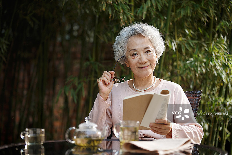 老年女人坐在院子里读书图片素材