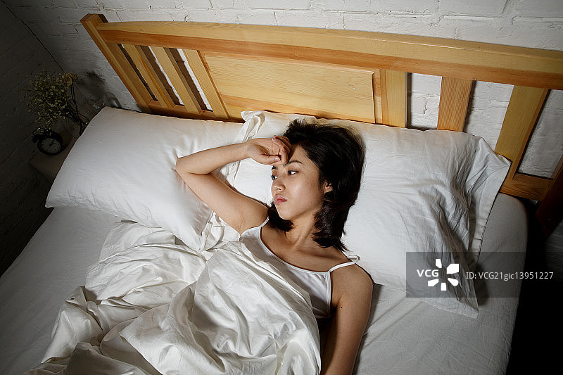 青年女人躺在床上失眠图片素材