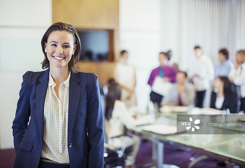 会议室里微笑的年轻女商人肖像，背景是人群图片素材