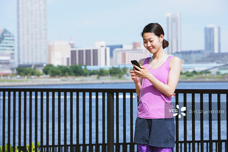 在东京市中心跑步前使用智能手机的年轻日本女性图片素材