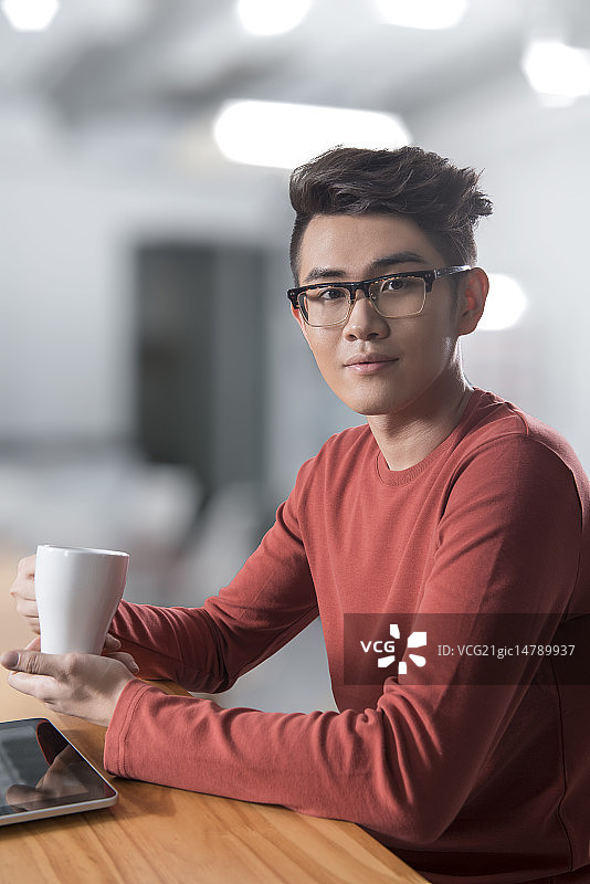 Creative businessman drinking coffee in break room图片素材