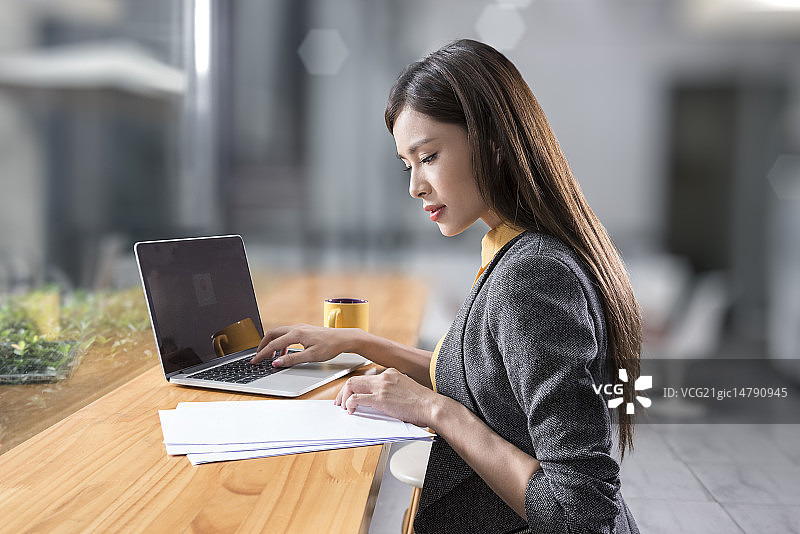 Creative businesswoman using laptop in break room图片素材