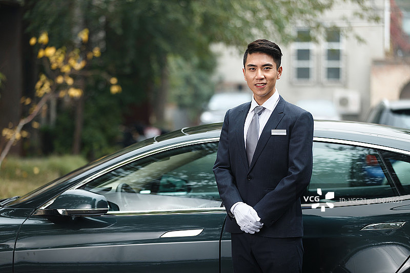 年轻的男招待站在车前图片素材
