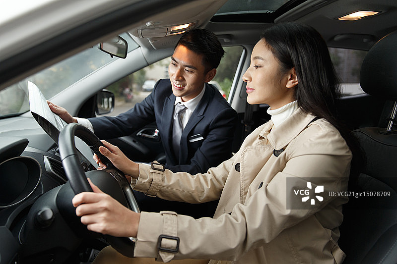 汽车销售员协助青年女人在试驾新车图片素材