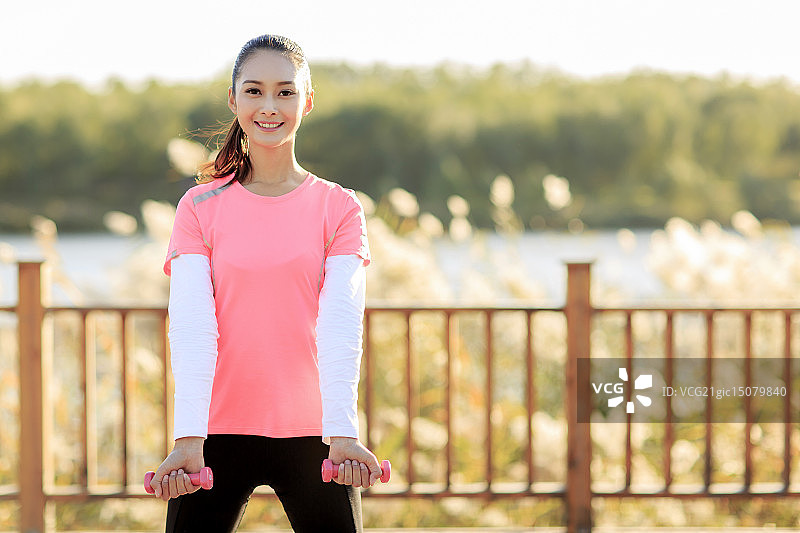青年女人在户外做哑铃操图片素材