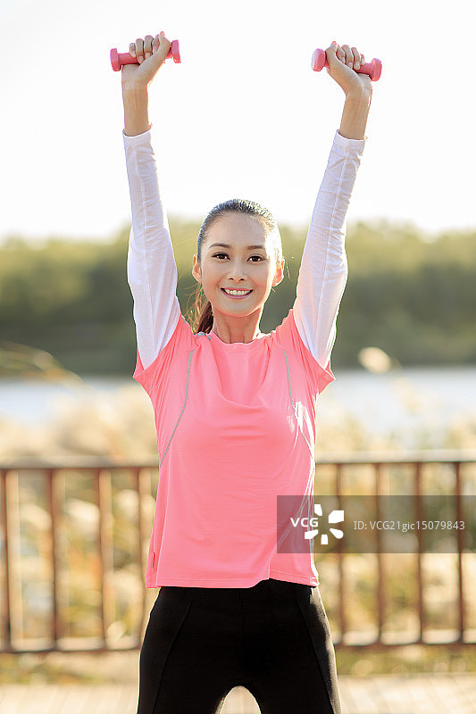 青年女人在户外做哑铃操图片素材