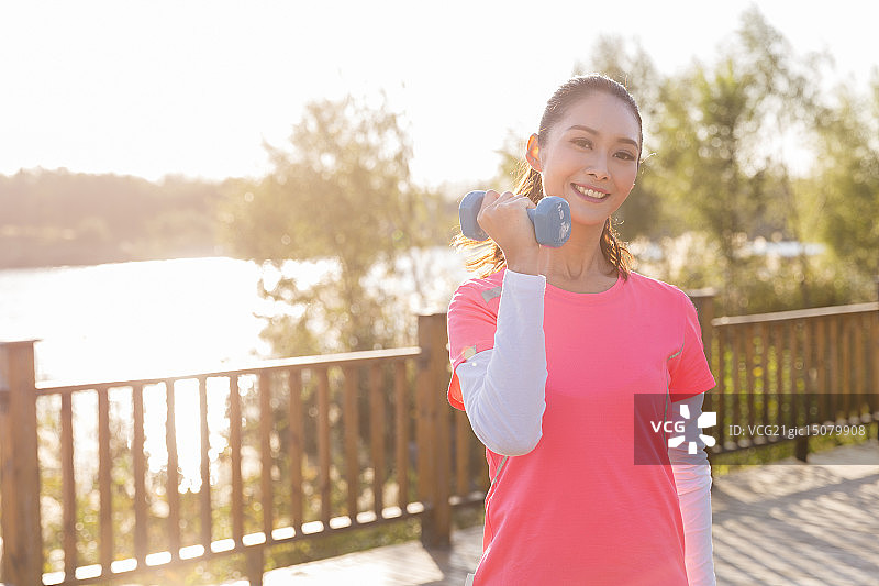 青年女人在户外做哑铃操图片素材