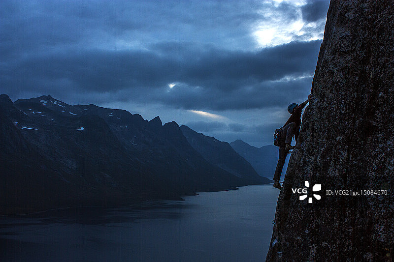 男子在挪威特罗姆瑟的夜晚攀登悬崖图片素材