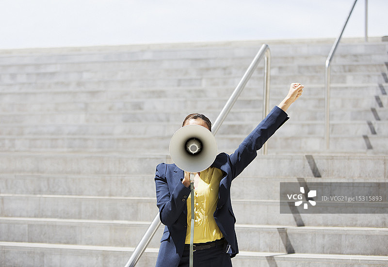 在城市台阶上使用扩音器的女商人图片素材