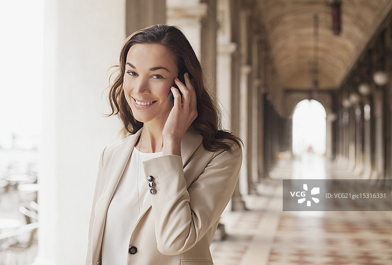 在走廊里用手机交谈的微笑女商人肖像图片素材