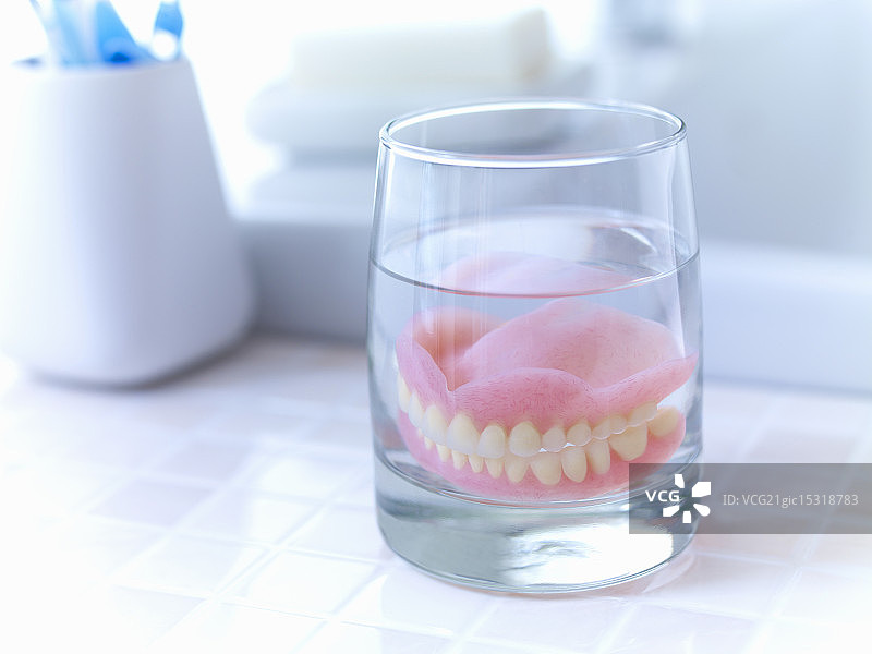 浸泡在水杯中的假牙特写图片素材