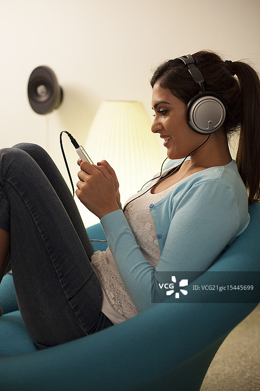 在客厅听音乐的新加坡年轻女人图片素材