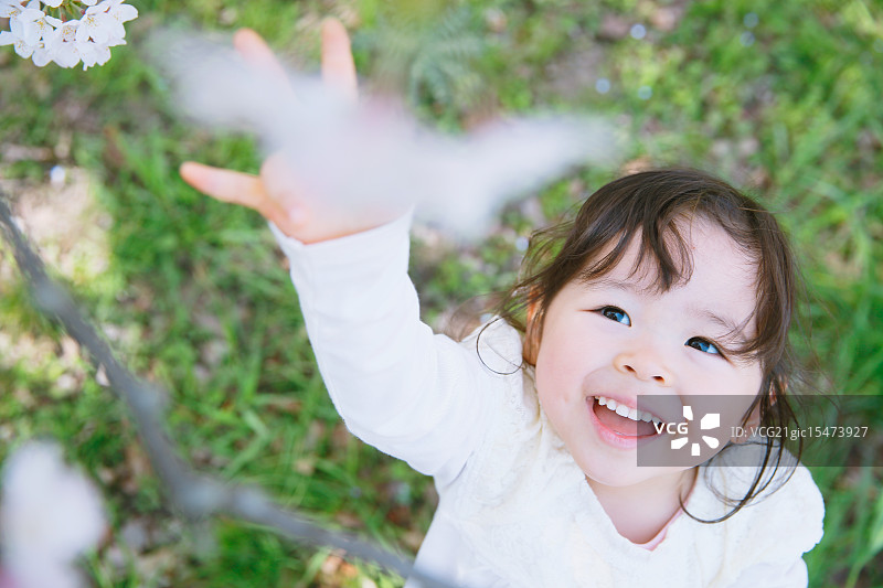 在城市公园里欣赏樱花的年轻微笑日本女孩图片素材