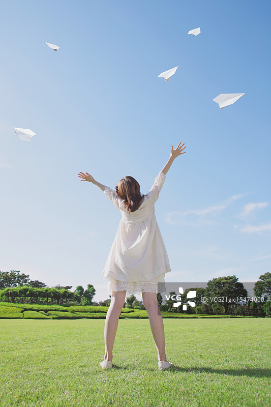 一个日本女人在城市公园里驾驶纸飞机图片素材