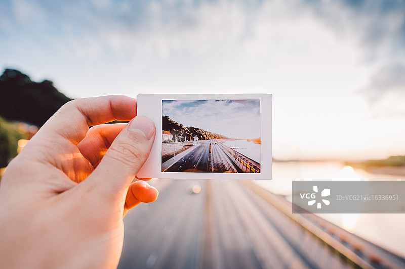 手持宝丽来照片，背景是高速公路图片素材