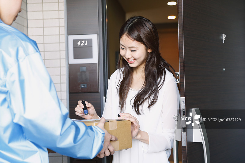 日本年轻女子从送货员那里收到包裹图片素材